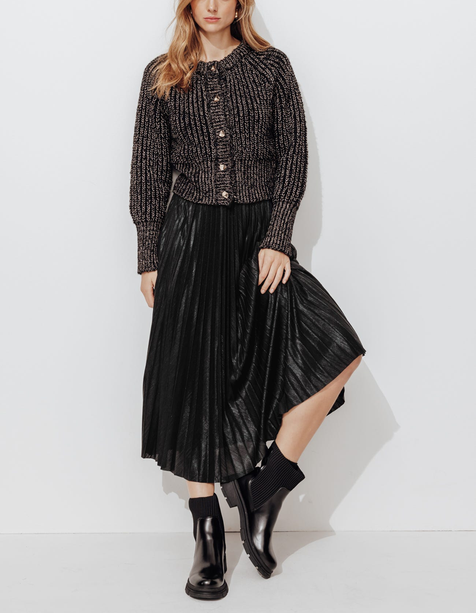 mannequin portant un total look monochrome noir dont une jupe longue plissé noir, un cardigan et des boots noires