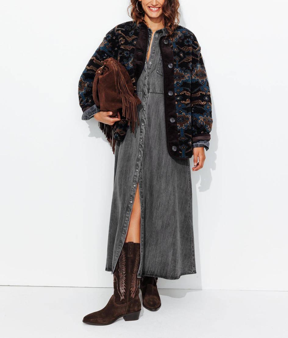 mannequin portant une robe chemise longue grise, avec un manteau en moumoute, des bottes western et un sac à frange