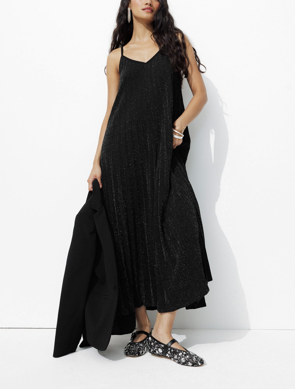 mannequin portant une robe longue noir avec des bijoux et une veste de costume, avec des ballerines habillées 