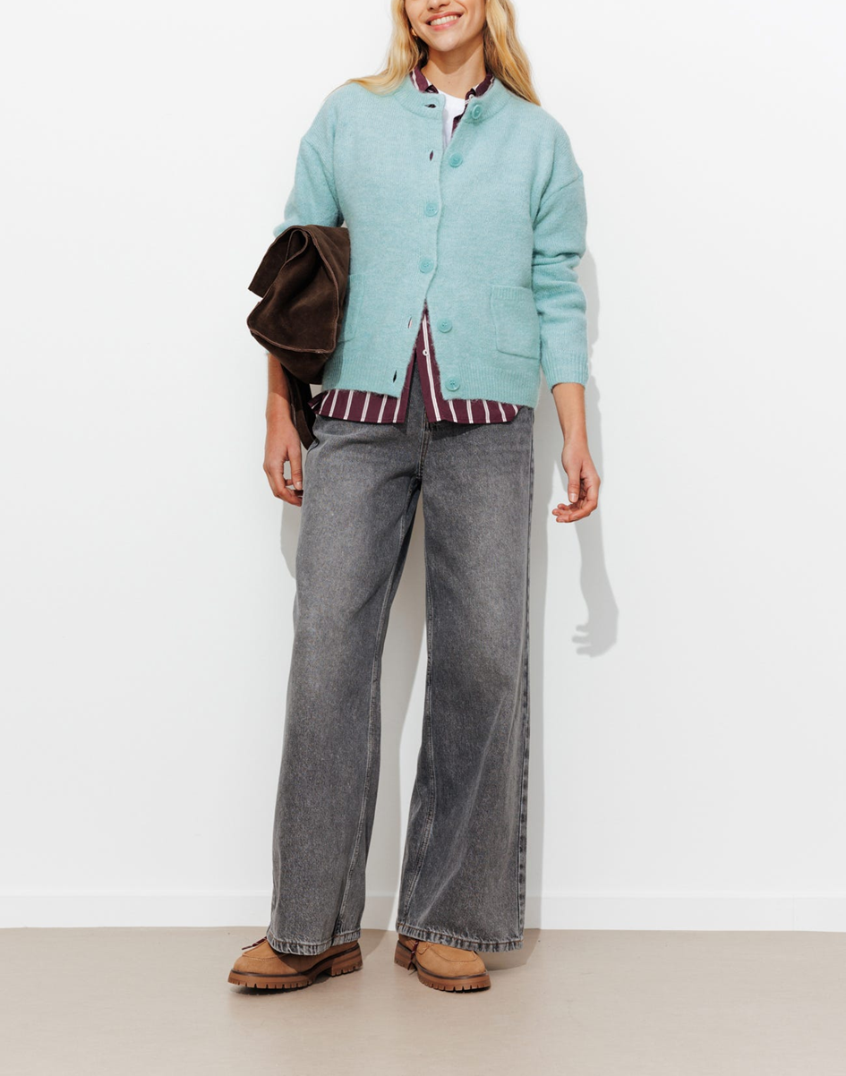 mannequin portent un cardigan vert clair avec une chemise bordeaux à rayure, un jean gtris clair 