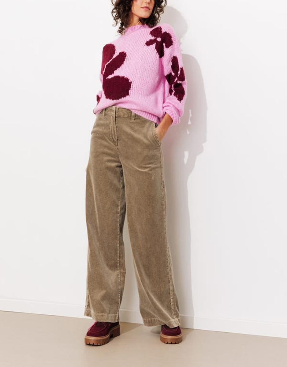 mannequin portant un pull rose avec des fleurs bordeaux et un pantalon large en velours beige