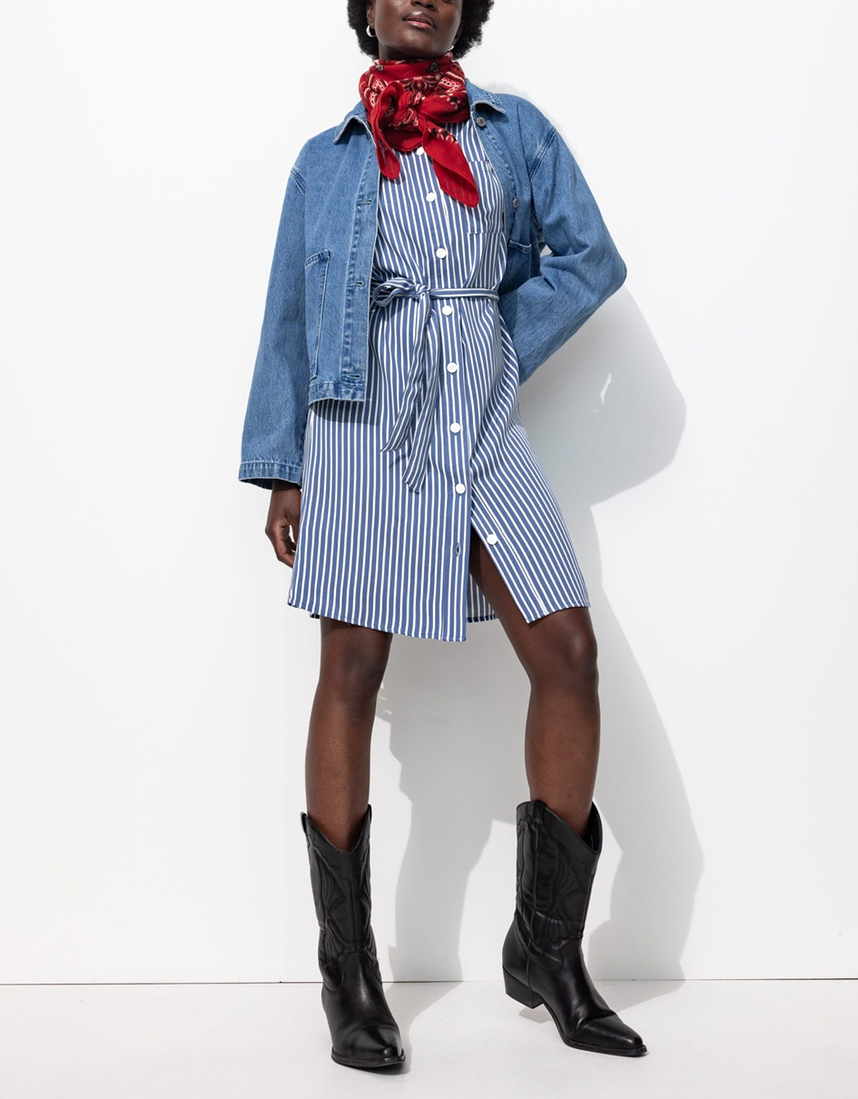 Mannequin portant une robe chemise courte rayée avec des manches courtes, avec une veste en jean, un foulard et des bottes de western