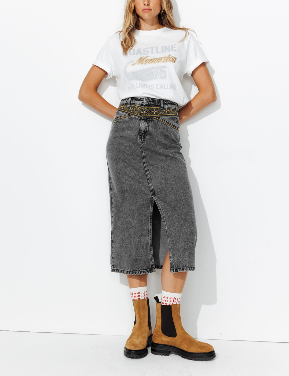 mannequin portant une jupe longue en jean avec un fente vertical avec un galon brodé au point de croix devant