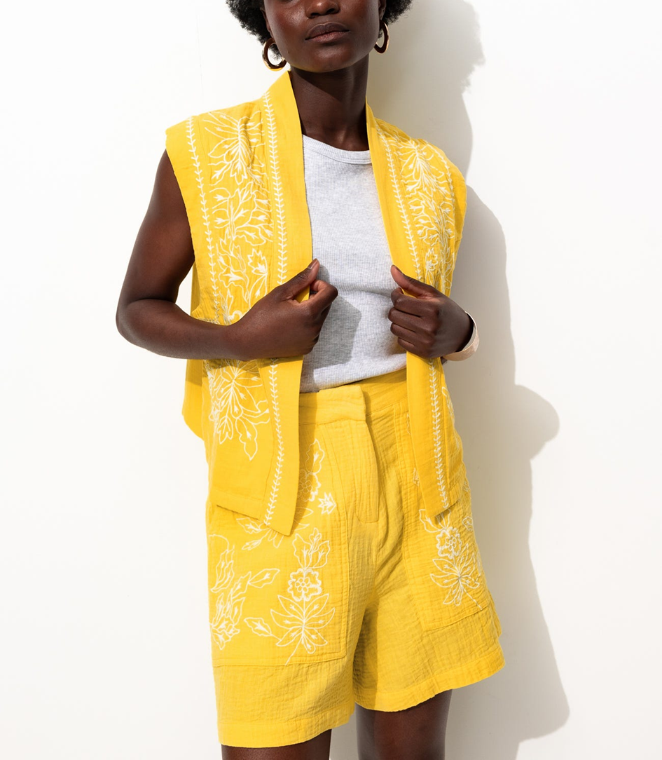 mannequin portant un ensemble veste sans manche et short en gaze de coton jaune brodé avec du blanc, avec un t-shirt grisen dessous