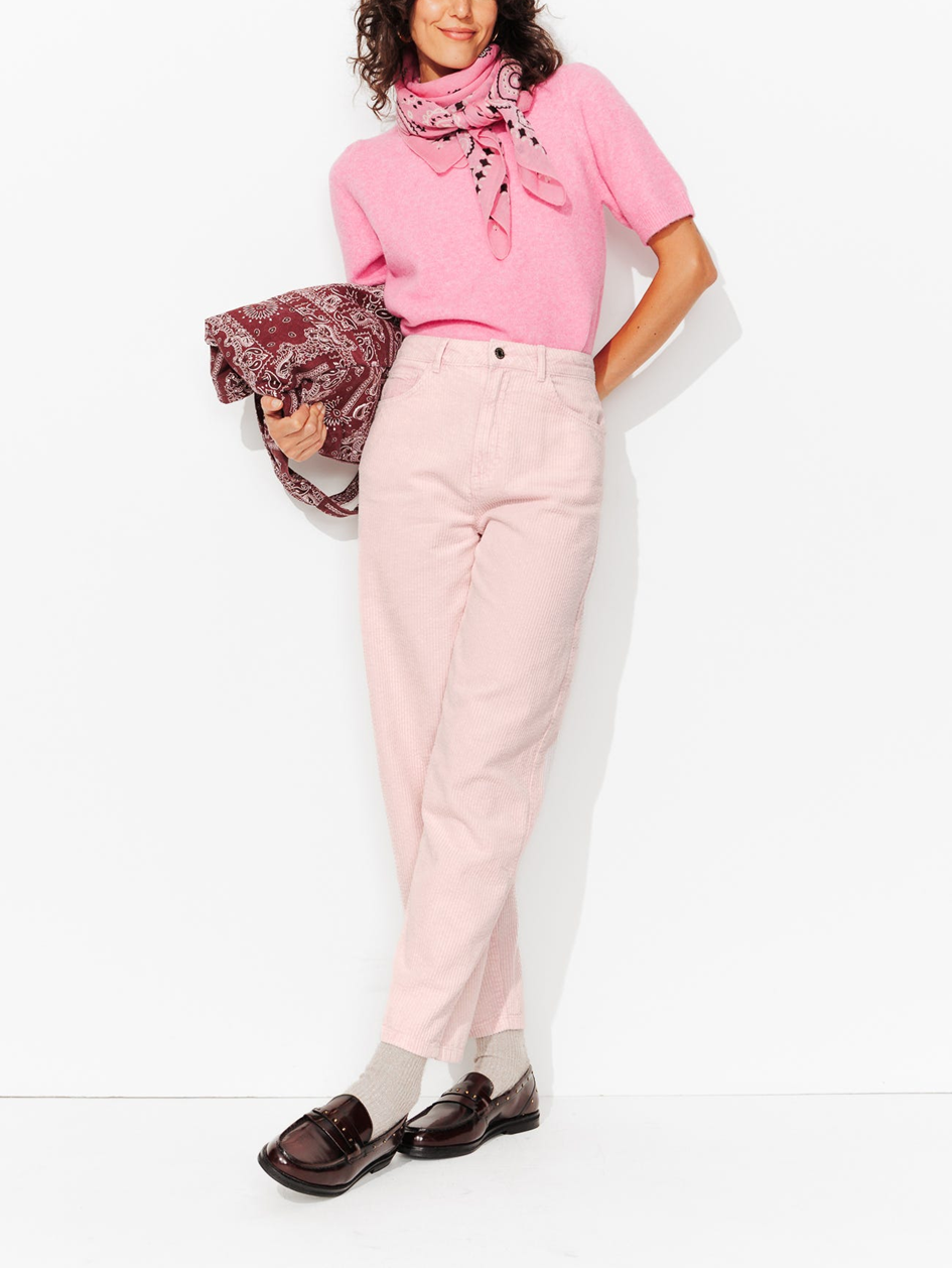 mannequin portant un look monochrome rose, avec un sac rose foncé et un foulard rose pâle