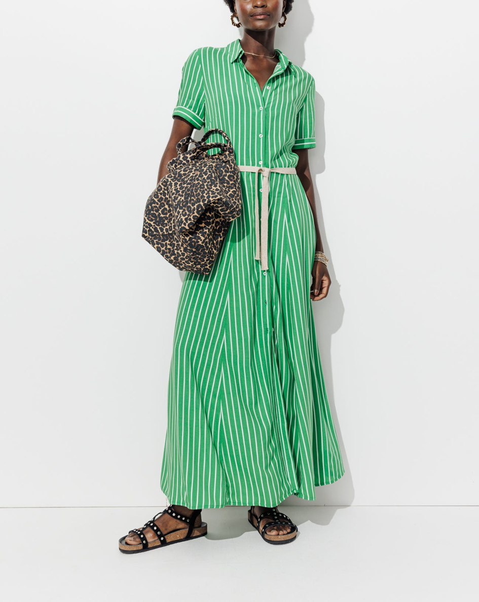 Mannequin portant une robe chemise longue rayé verte, avec une ceinture à la taille et un sac caba léopard, et portant des bijoux
