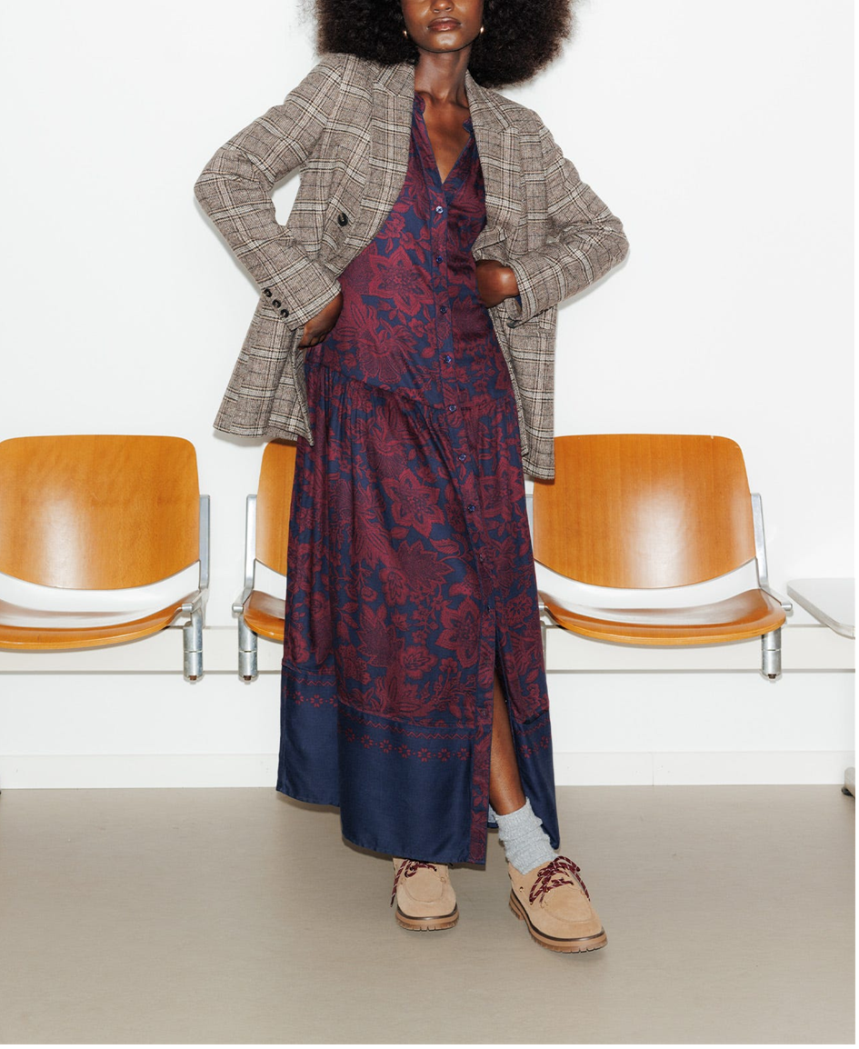 mannequin portant une robe longue imprimé avec un veste blazer à carreaux 