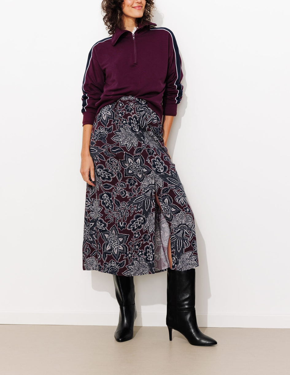 mannequin portant une jupe midi imprimée avec des bottes à talons et un sweat 