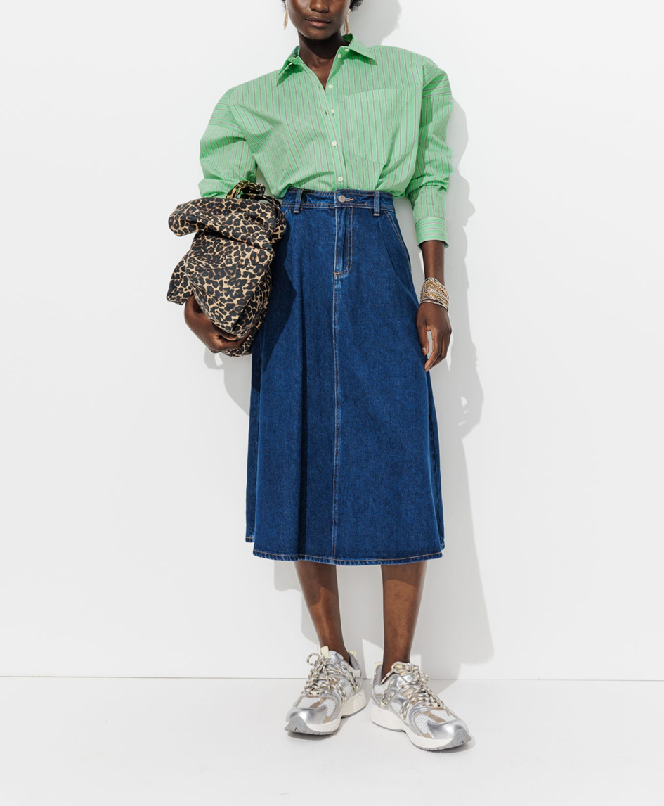 Mannequin portant une chemise verte à rayre avec une jupe midi en jean et un sac léopard 