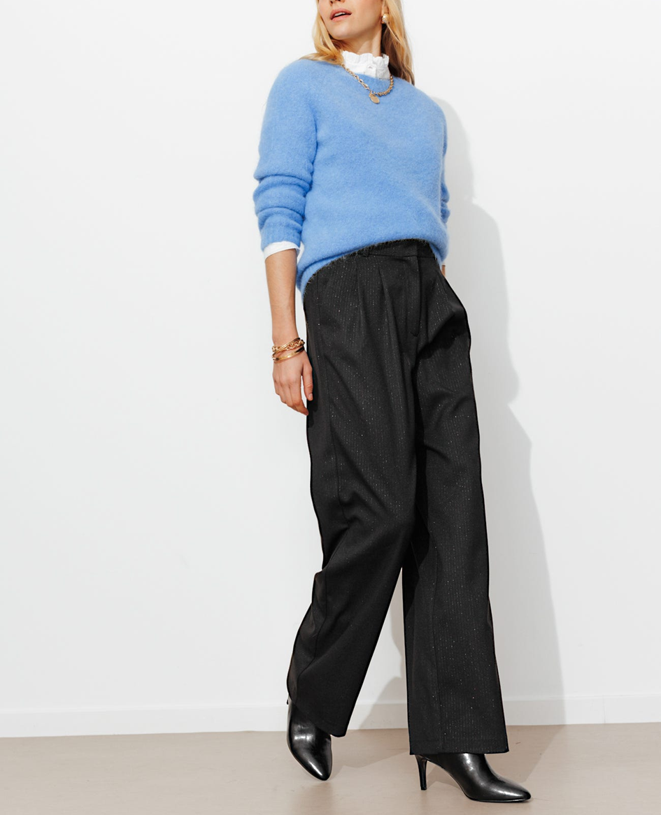 Mannequin portant un pantalon large à paillettes avec un pull et une chemise en dessous et des bottes à talons