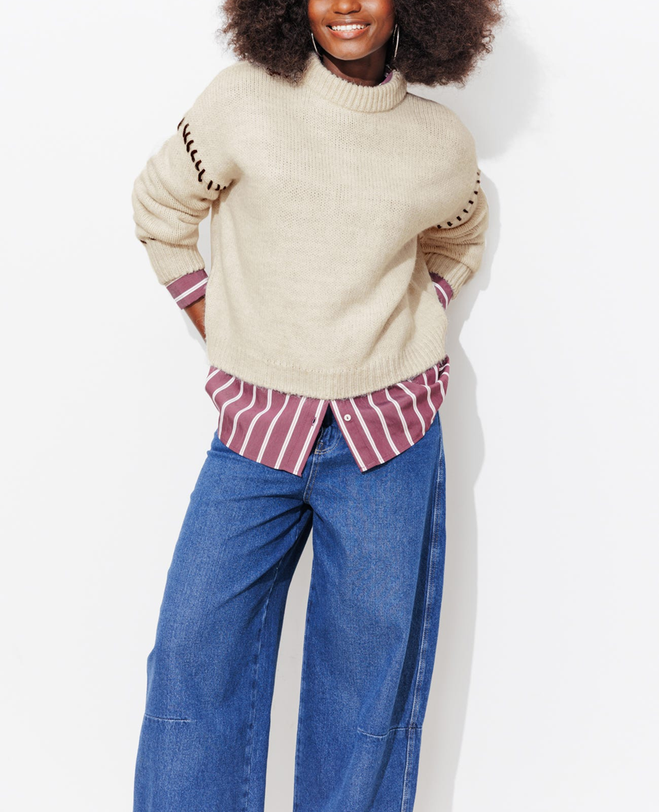 mannequin portant un pull court en maille, avec une chemise par dessous et un jean bleu barrel