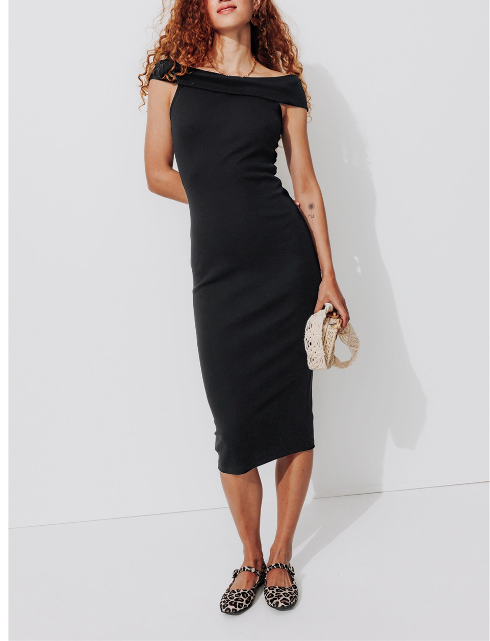 mannequin portant une robe mi-longue noir avec un sac à main et des ballerines léopard