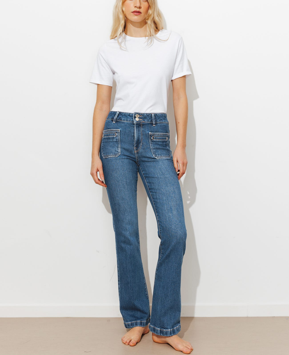 mannequin portant un jean flare seventies long, légèrement évasé en bas : il affine les jambes et élance la silhouette avec une taille haute et un denim épais, légèrement stretch. Passants. 2 boutons clou + zip. 6 poche