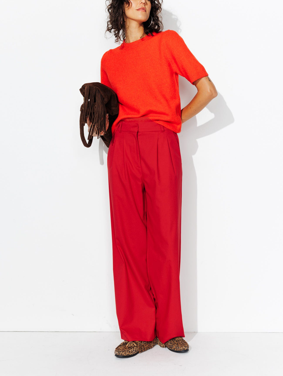 mannequin portant un total look monochrome rouge, dont un pull manche courte et un pantalon de tailleur. Avec un sac à franche 