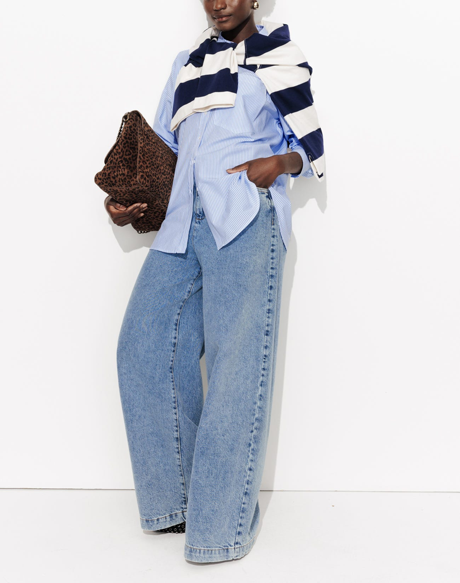 mannequin portant une chemise rayé avec un polo marinière sur les épaules et un sac léopard avec un jean