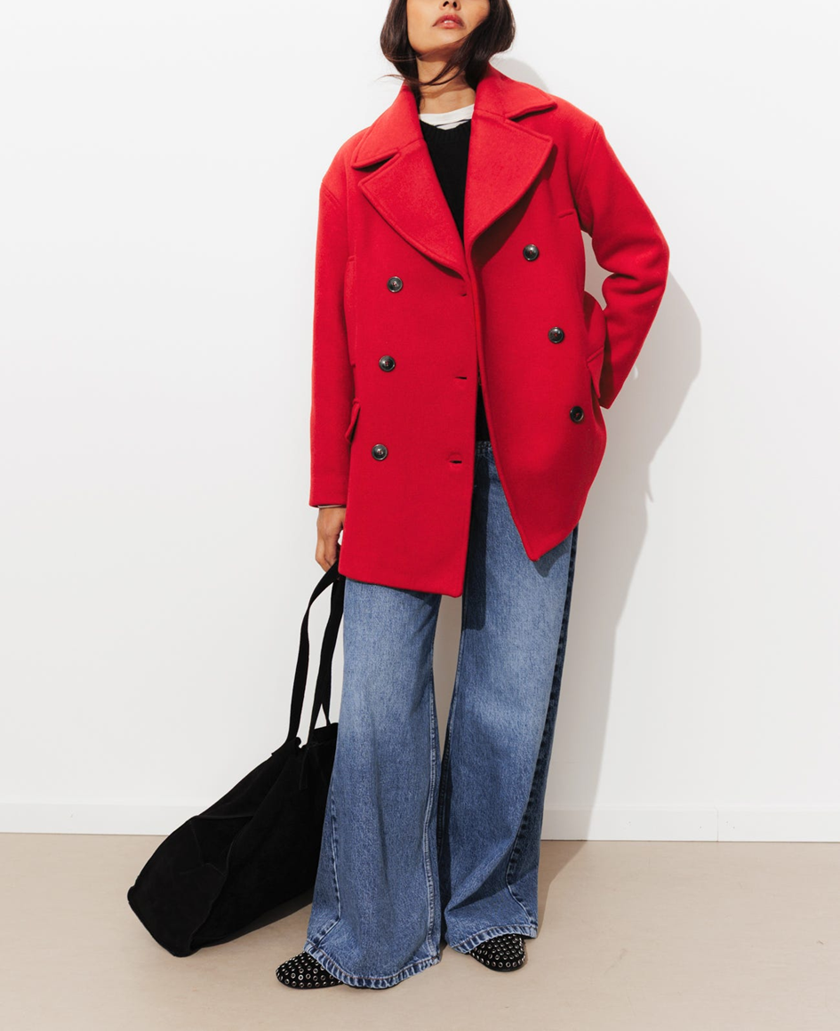 mannequin portant un manteau caban en laine roige avec un pull noir et un jean, accordé avec des ballerines noires et un sac noir 