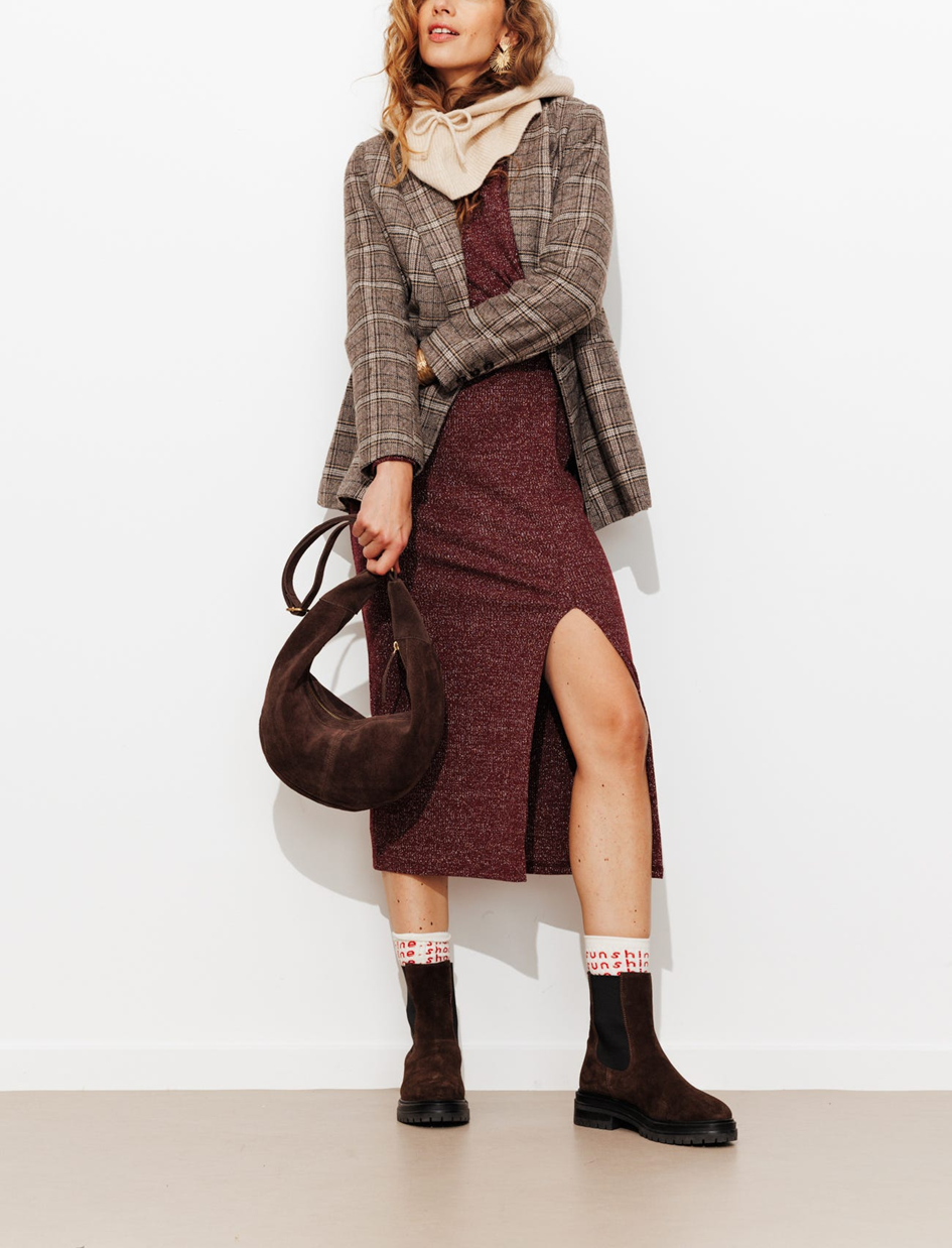 mannequin portant une robe noeud à paillettes avec une veste de tailleur, accessorié avec une cagoule et une sac lune, ainsi que des bottines et des chaussettes hautes   