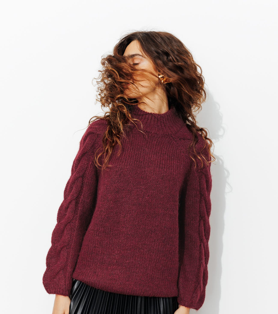 mannequin portant un pull col montant bordeaux Coupe légèrement resserrée à la base. Col montant côtelé. Emmanchures raglan, manches longues torsasées. Base droite. Bords-côtes. Maille enrichie en laine et en alpaga, pour plus de chaleur et de douceur.
