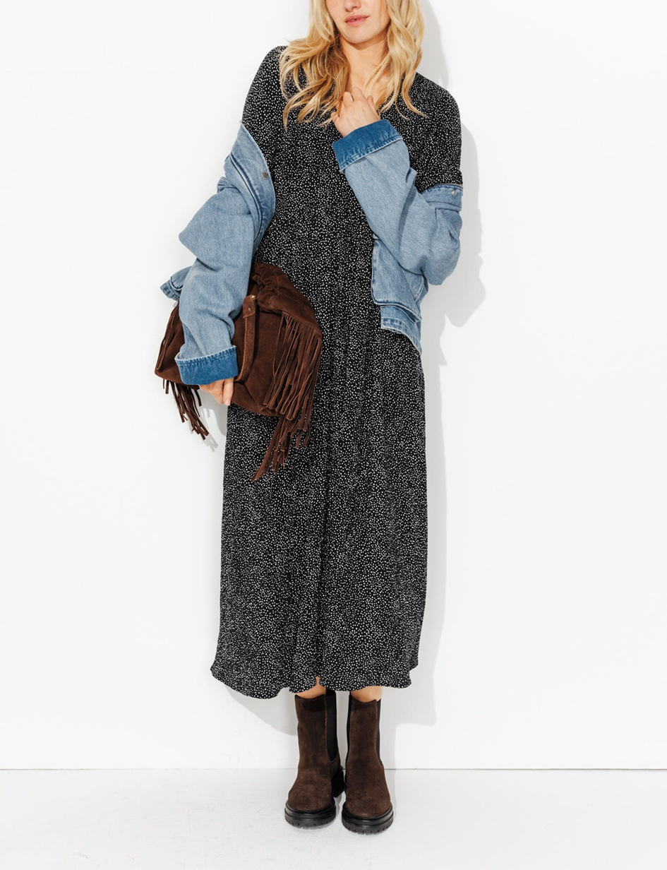 mannequin portant une robe longue imprimée avec un sac en cuir à franche et une veste en jean